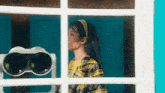 a woman in a plaid shirt is looking out of a window at a binoculars .