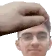 a hand is touching a man 's head with glasses .