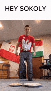 a man wearing a red shirt with an eagle on it is dancing in front of a flag that says hey sokoly