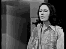 a black and white photo of a woman wearing a vest and a shirt .