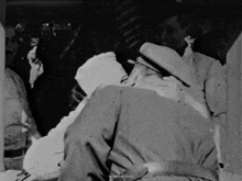 a black and white photo of a man laying on a bed with a caption that says marcel wood