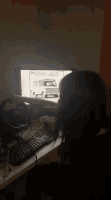 a woman is sitting in front of a computer screen with a truck on it and a sign that says ' a ' on it
