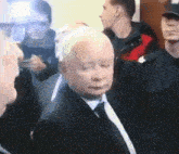 a man in a suit and tie is surrounded by people