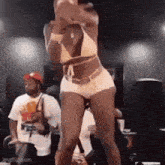 a woman in a bikini is dancing on a stage in front of a group of people .