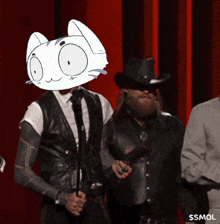 a man wearing a cat mask stands next to a man in a cowboy hat and a man in a leather vest