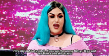 a drag queen with blue hair and a choker is talking to a person .