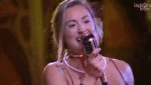 a woman is singing into a microphone while wearing a choker .