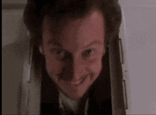 a man in a suit and tie is smiling and looking out of a doorway .