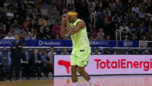 a basketball player stands on the court in front of an ad for total energy