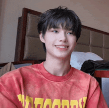a young man wearing a red shirt that says woody smiles for the camera