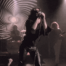 a man singing into a microphone in front of a swirl background