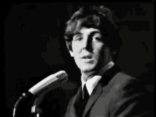 a man in a suit and tie is standing in front of a microphone .