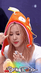 a woman is wearing a fish hat and holding a ring .
