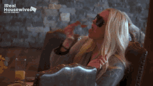 a woman wearing sunglasses sits at a table with the words real housewives out of context above her