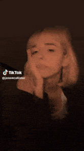 a woman in a white tank top is making a tik tok video
