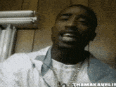 a close up of a man wearing a white shirt and a chain with the name thamakavelis written on the bottom