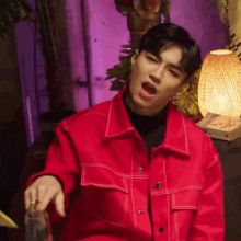 a young man in a red jacket is holding a glass of water