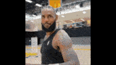 a man with a beard is standing on a basketball court with a basketball hoop in the background .