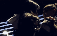 two women are sitting next to each other in a dark room and laughing .