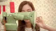 a woman is using a green sewing machine to sew something