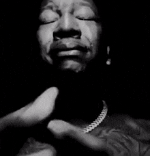 a man is praying in a black and white photo with his hands folded in prayer .