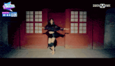 a woman is dancing in front of a red door with a sign that says sixteen