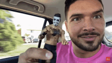a man in a pink shirt is holding a figurine of a wrestler