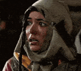 a woman wearing a scarf around her head is making a sad face .