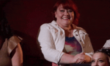 a woman with red hair and a white jacket is smiling