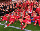 a group of soccer players posing for a photo with a trophy