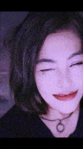a close up of a woman 's face with her eyes closed and a choker necklace