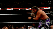 a wrestler in purple pants is doing a handstand in a ring