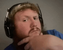 a man with a beard wearing headphones and a microphone is making a funny face .
