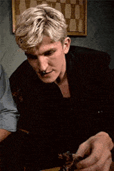 a man in a black jacket is holding a kitten in his hand .