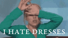 a woman in a green shirt is covering her face with her hands and the words `` i hate dresses '' are written below her .