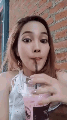 a woman drinking from a cup with a straw in her mouth