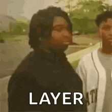 a man in a black jacket is standing next to a man in a white shirt and says `` layer '' .