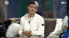 a man sitting on a couch with a m+ logo on the bottom right