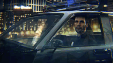 a man is driving a police car with a suitcase on the roof