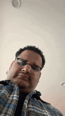 a man wearing glasses and a plaid shirt makes a funny face