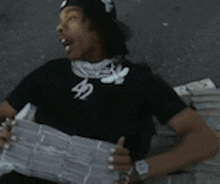 a man wearing a black shirt with the number 42 on it is reading a newspaper .