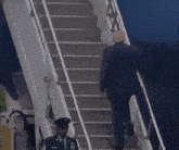 a man in a suit climbs the stairs of a plane