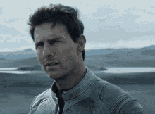 a man in a leather jacket is standing in a desert .