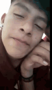 a close up of a young man 's face with his eyes closed and his hand on his face .