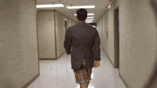 a man in a suit walks down a hallway