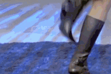 a person wearing a pair of black boots is walking on a blue surface .