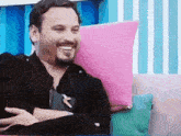 a man with a beard is smiling while sitting on a pink couch