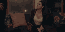 a woman is sitting on a couch crying while looking at a laptop computer .