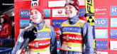 two athletes are standing next to each other in front of a wall with advertisements for ylo and hyl