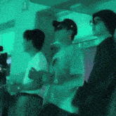 a group of people standing in a room with a green light behind them